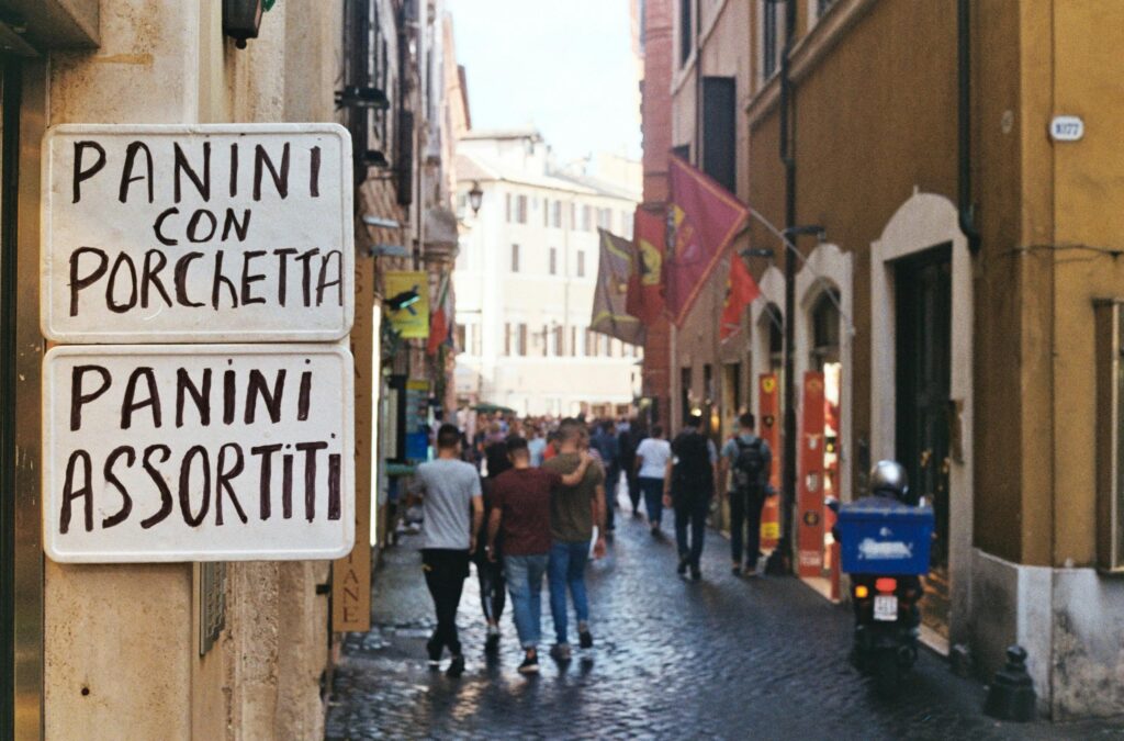 A bustling street in Rome featuring a panini restaurant sign and pedestrians enjoying the day.