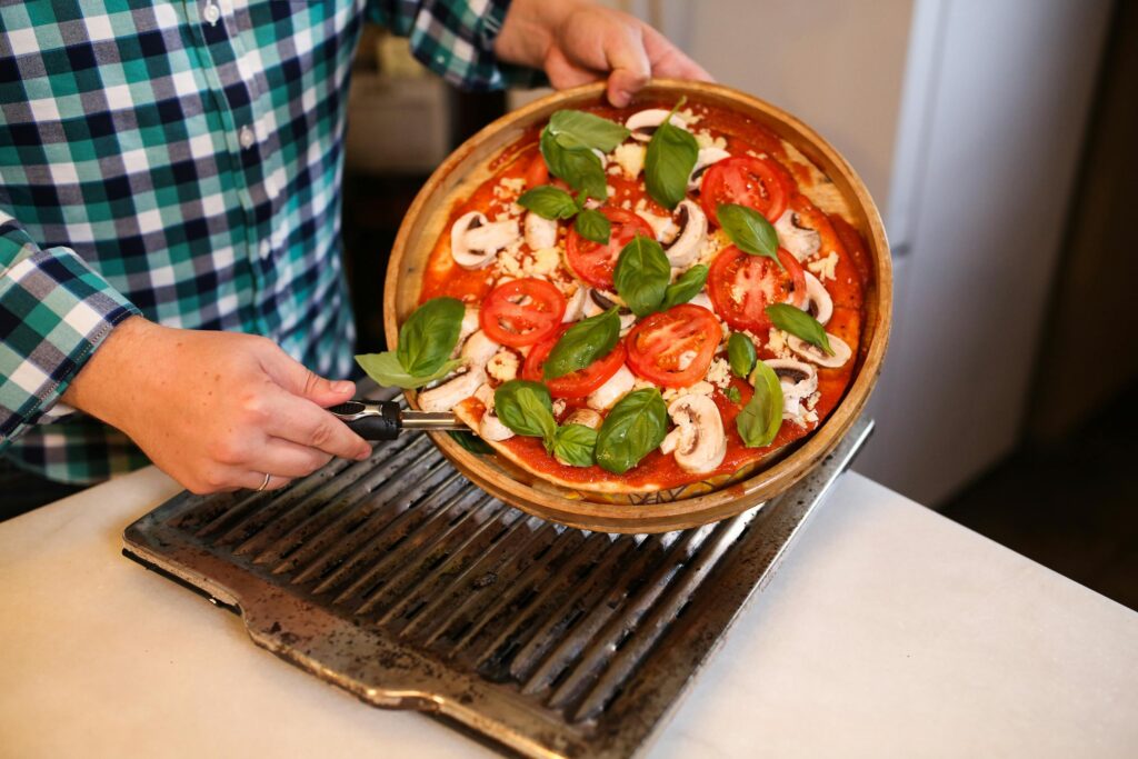 A delicious homemade pizza topped with fresh basil, tomatoes, and mushrooms, ready for baking.