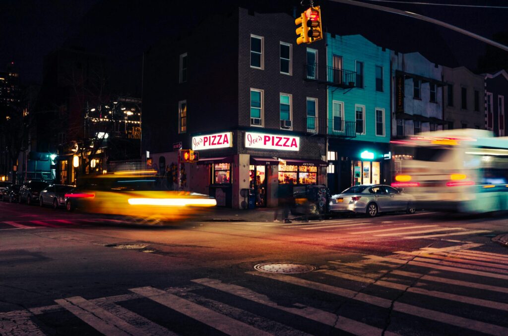 A lively New York City street at night with motion blur capturing the city's energy.
