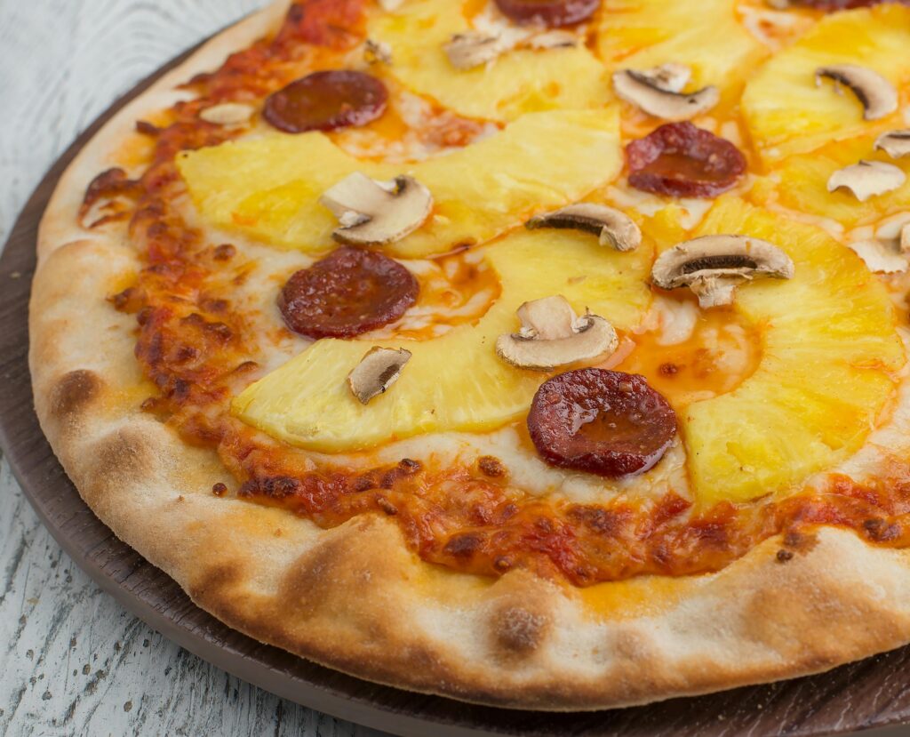 Delicious pizza topped with pineapple, pepperoni, and mushrooms, perfect for lunch or dinner.